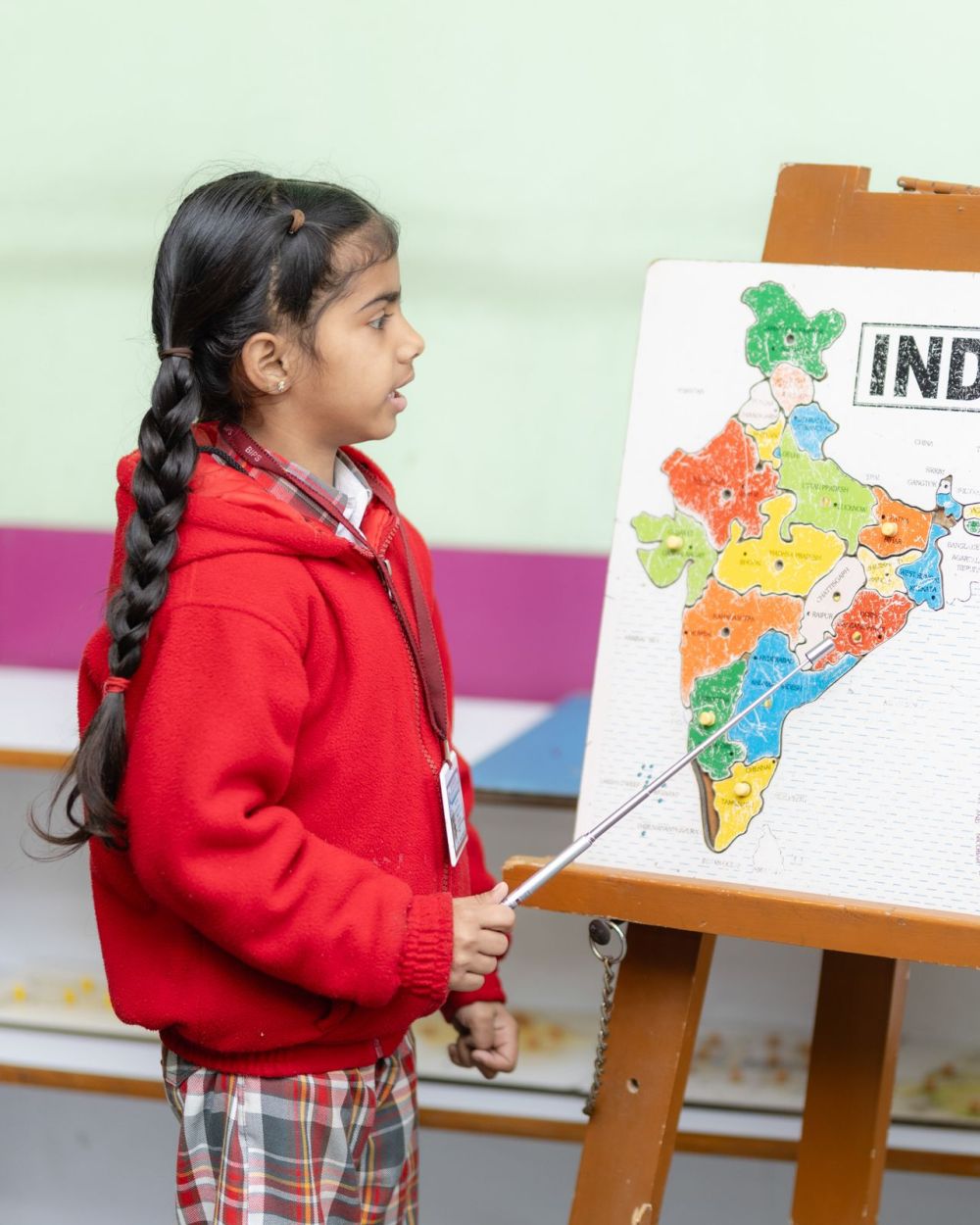 A young student confidently presenting a map of India to her class